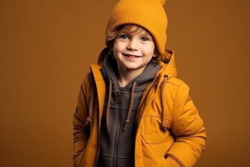 Wall Mural - Portrait of a cute little boy in a yellow jacket and hat