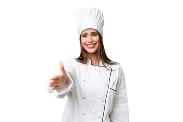 Wall Mural - Young chef caucasian woman over isolated background shaking hands for closing a good deal