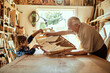 © Marko Geber - Grandfather and grandson building a wooden model in a workshop