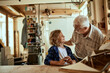 © Marko Geber - Grandfather and grandson building a wooden model in a workshop