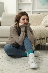 Wall Mural - Sad young woman sitting on floor at home