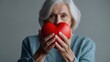 © Shivamrajput46  - Elderly senior person or grandparent's hands with red heart in support of nursing family caregiver for national hospice palliative care and family caregivers month, World Nurses day concept.