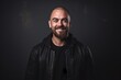 © Loli - Smiling bald man in a black leather jacket on a dark background