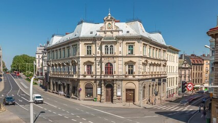 Wall Mural - Busy traffic on intersection near Chrobry Square in Bielsko-Biala timelapse, Poland. Historic buildings aerial view from Sulkowski Castle. People crossing the road. Sunny day with a blue sky