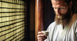 Close-up portrait of a bearded man in a kimono drinking coffee
