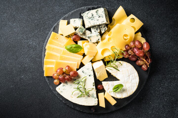 Sticker - Cheese platter with craft cheese assortment and grape at black background. Top view with copy space.