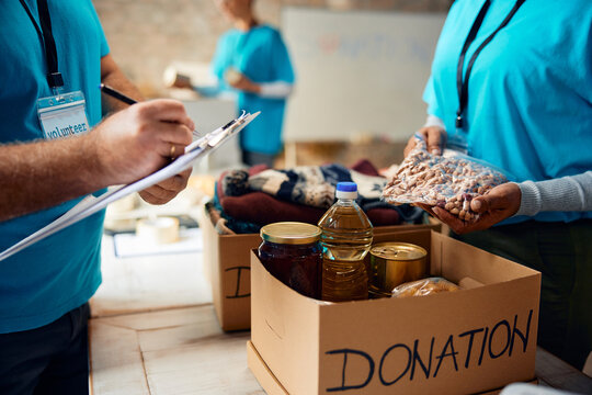Close up of charity workers sorting donations into boxes at humanitarian aid center.