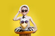 Boy in summer panama and sunglasses with inflatable swimming circle on yellow background