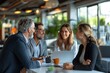 © Joaquin Corbalan - Four businesspeople actively engaged in a discussion while sitting around a table.