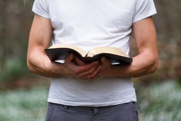 Person holding holy bible book, religion concept.