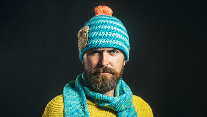 Wall Mural - Portrait of serious bearded man in yellow sweater, blue scarf and hat. Autumn-winter fashion. Casual look. Fashionable man in winter clothes. Handsome man in knitted hat and scarf. Winter accessories.