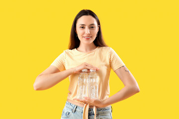 Wall Mural - Young woman with bottles of water on yellow background