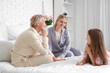 © Pixel-Shot - Little girl with her mom and grandmother talking in bedroom