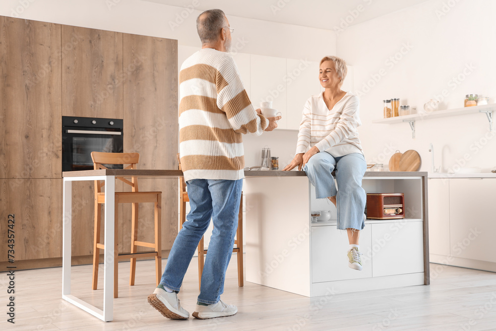 Mature man bringing coffee to his wife in kitchen