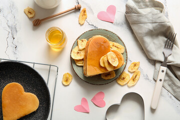 Wall Mural - Plate with tasty pancakes in shape of heart, dried banana and honey on light background. Valentine's Day celebration