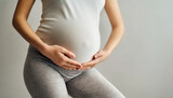 Fototapeta  - pregnant woman's belly and genital area in light grey tights, symbolizing fertility, hope, and impending motherhood