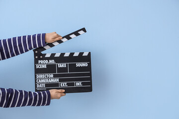 Wall Mural - Female hands with movie clapper on blue background