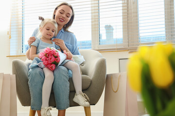 Wall Mural - Little girl with her mother and bouquet of tulips at home. International Women's Day