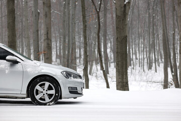 Wall Mural - Car with winter tires on snowy road in forest, space for text