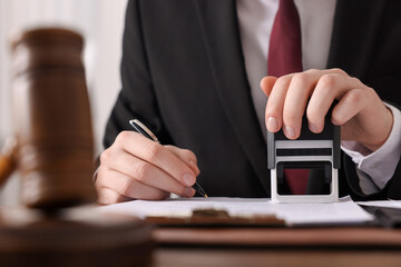 Canvas Print - Notary with pen stamping document at table in office, closeup