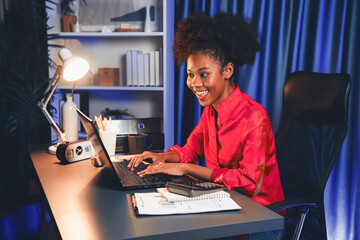 Wall Mural - African woman blogger wearing pink shirt with happy face, looking on screen laptop with valued achievement project or get scholarship. Concept of cheerful expression work from home. Tastemaker.