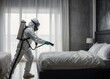 man in a mask sprying for viruses in room