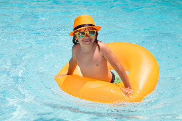 Wall Mural - Summer child in swimming pool. Summer vacation concept. Summer kids portrait with floating ring in sea water on beach.