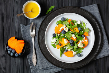 Wall Mural - arugula persimmon cheese berries salad, top view