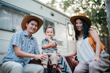Wall Mural - An Asian multiracial family with children are camping in nature on a road trip. Dad and mom daughter and son in the woods in the summer. Selective focus