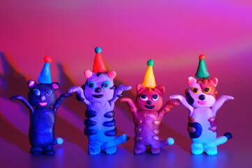 Sticker - Funny toy cats in festive hats stand on their hind legs. Color background.