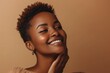 Happy black woman with short hair caressing her smooth neck skin attractive African American lady relishing beauty treatments standing against brown background