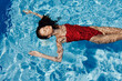 © SHOTPRIME STUDIO - Young woman in the pool in a red swimsuit with a beautiful smile lying on the water and swimming in the sun swimming in the pool, the concept of relaxing on vacation.