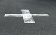 White cross sign on asphalt road