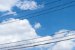 Electrical cable wires against white cloud and blue sky background, copy space