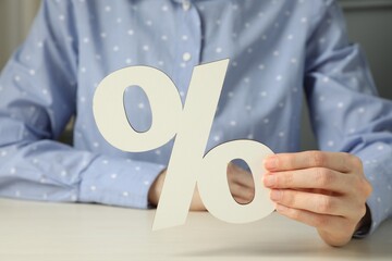 Woman holding percent sign at white wooden table, closeup