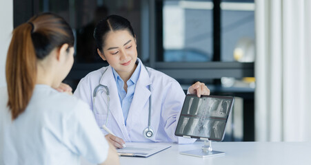 Wall Mural - Asian female doctor explain to patient and looking at xrays indoors office, healthcare and medical concept.