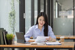 © SOMKID - Happy asian accounting businesswoman working in office working space, Asian female employee using laptop at workplace.