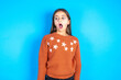 Shocked Young beautiful teen girl wearing orange knitted sweater stares bugged eyes keeps mouth opened has surprised expression. Omg concept