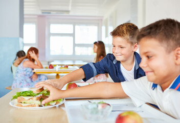 Wall Mural - Smiling male students sharing sandwiches in school