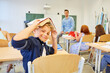 Smiling schoolkid with book on head in classroom