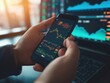 © CG Design - A close-up of hands holding a smartphone with a finance app, tracking investment portfolios and monitoring market performance