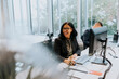 © Maskot - Cheerful senior businesswoman sitting at computer desk while looking away in office