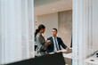 © Maskot - Smiling businessman and businesswoman talking in office