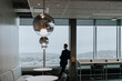 © Maskot - Rear view of businessman looking out through window at office