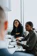 © Maskot - Smiling senior businesswoman sitting by female colleague in board room during meeting