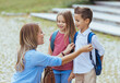 © Dragana Gordic - Mother saying goodbye to her little children near school. Mother taking kids to school. Beginning of lessons. First day of fall.
