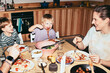 © Maskot - Playful kids having meal with parents while sitting at dining table in home