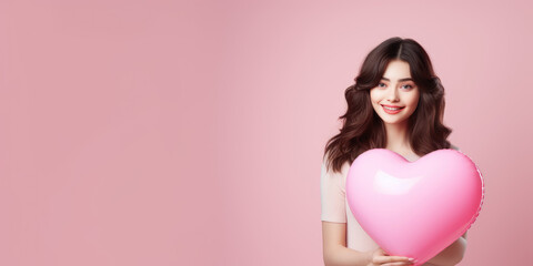 Wall Mural - girl holding pink heart shaped balloon on pink banner. Valentine's day concept