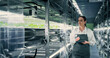 © Gorodenkoff - Biology Scientist Working at Vertical Farm Next to Rack with Natural Eco Plants. Female Farming Engineer Using Tablet Computer, Organizing and Analyzing Crops Information Before Distribution