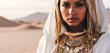 beautiful young girl with white cowl and golden ethnic jewelries looks intently at the camera. Woman in the hood and clothes for the desert, close up fantasy beauty portrait